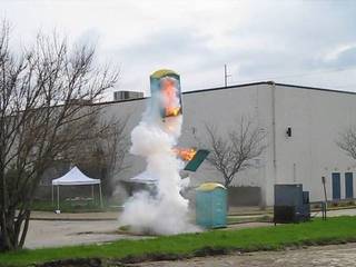 A white plume rises around a small public bin or fixture.