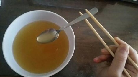 Soup bowl staged with chopsticks and spoon.