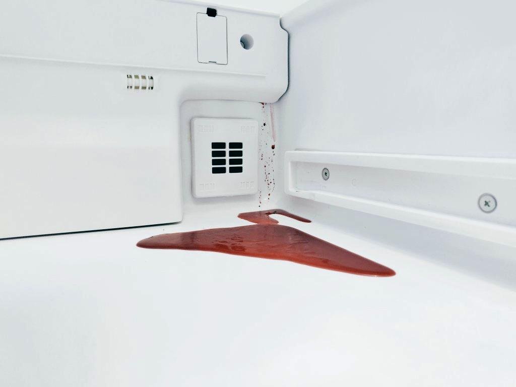A red beetroot spill pools inside a white refrigerator.