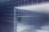 Blue tiled walls and rectangular openings seen through rippled water as empty flooded passages.