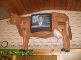 A cow-shaped wall display frames a television indoors.