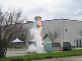 A white plume rises around a small public bin or fixture.