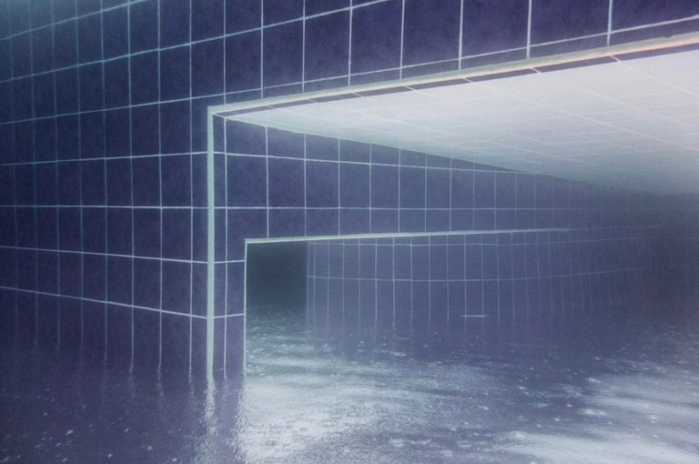 Blue tiled walls and rectangular openings seen through rippled water as empty flooded passages.